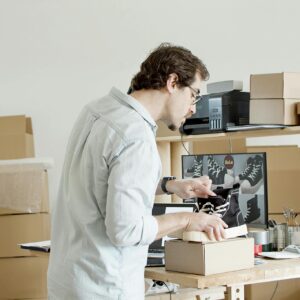 A businessman working in an online store packing shoes in a cardboard box.